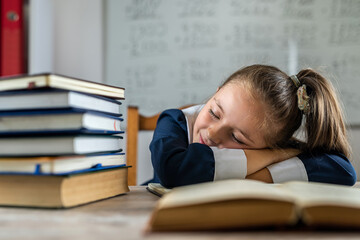 little student is sleeping on the school desk because she is tired.