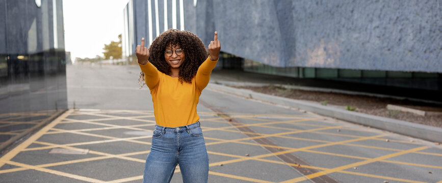 Happy young woman showing middle finger at footpath