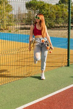 Young woman wearing sunglasses standing at sports court
