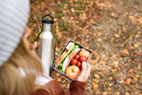 Woman holding food box and stainless steel bottle on weekend