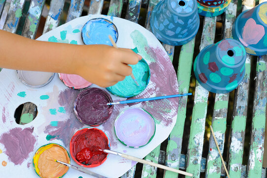 Hand of little girl painting flower pots