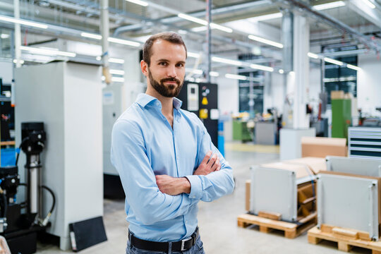 Smiling businessman with arms crossed at factory