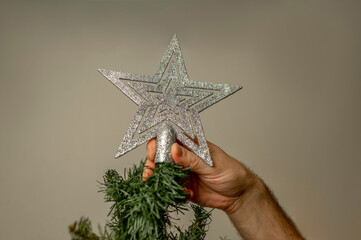 Hand of man decorating Christmas tree with silver star