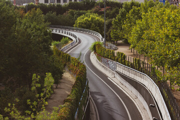 Winding paved empty road goes into distance among trees aerial view. A highway.