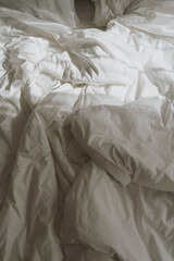 Comfortable white crumpled bed linens with sunlight shadows reflections. Morning in bed concept - obrazy, fototapety, plakaty