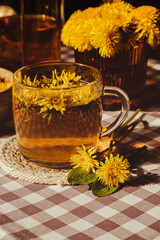 Dandelion flower healthy tea in glass teapot and glass cup on table. Delicious herbal tea from...