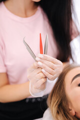 Woman doing eyebrow correction and lamination in beauty studio. Blond hair model has staining,...