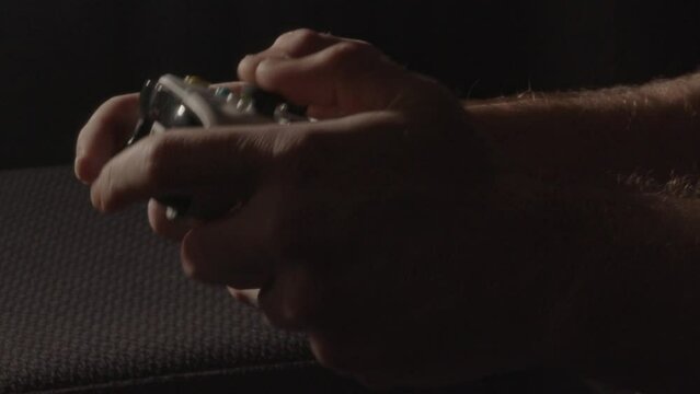 Hands playing aggressively on a videogame controller in a dark living room