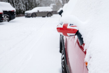 Snowy street and cars. British flag on the car mirror