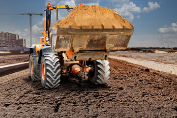 Bulldozer or loader moving sand on a construction site during the construction of a new road. An earthmoving machine is leveling the site. Construction equipment for earthworks. Territory improvement.