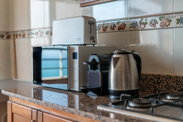 A coffee maker, a microwave and an electric kettle on the shelf in the kitchen