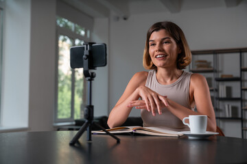Smiling businesswoman in casual wear making video blog using smartphone