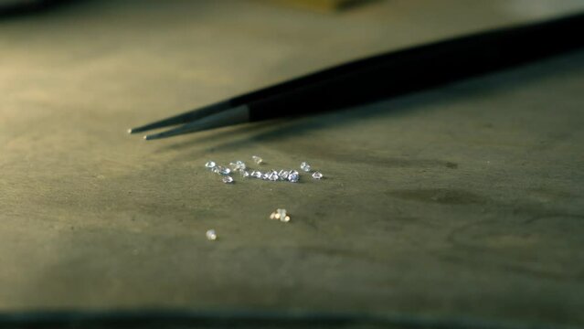 Diamond in tweezers. Craft jewelery, professional tools. Ring repairing. Macro shot. 
