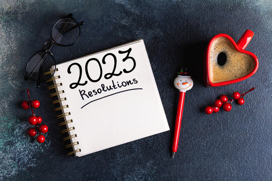 New year resolutions 2023 on desk. 2023 resolutions list with notebook, coffee cup, decorations on table. Goals, resolutions, plan, action concept. New Year 2023 background. Copy space