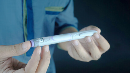 partially blurred picture of  man holding insulin pen. Medical equipment is easy to self injection