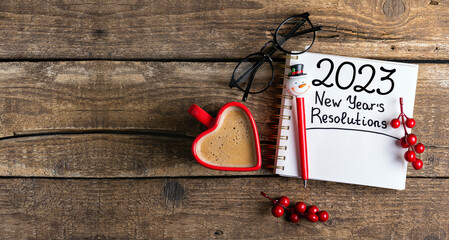 New year resolutions 2023 on desk. 2023 resolutions list with notebook, coffee cup, decorations on...