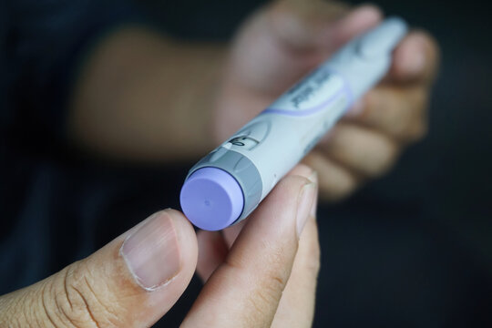 partially blurred picture of  man holding insulin pen. Medical equipment is easy to self injection