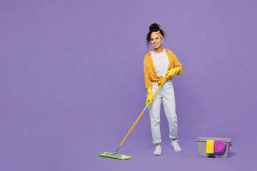 Full body young housekeeper woman wear yellow shirt tidy up hold mop bucket with water wash floor and clean house look camera isolated on plain pastel light purple background studio Housework concept