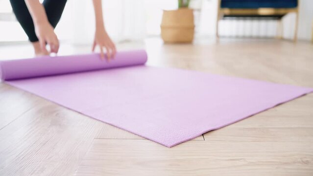Close-up young woman hands rolling yoga mat with water bottle, preparing for doing yoga. Working out at home or in yoga studio. Healthy habits, keep fit, weight loss concepts.