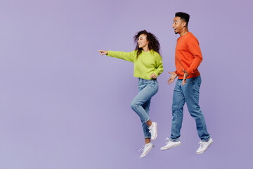 Full body side view young couple two friend family man woman of African American ethnicity wears casual clothes together point index finger aside workspace isolated on pastel plain purple background.