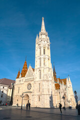 Facade with tower of Matthias Church or The Church of the Assumption of the Buda Castle during sunny day with blue sky in Budapest