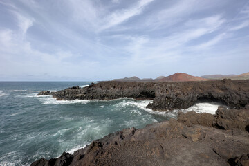 Fototapeta na wymiar Vista del paisaje volcánico en Los Hervideros (Lanzarote, Spain): olas del mar y volcanes