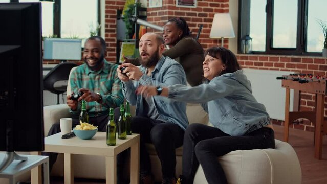 Diverse people winning video games on console, playing online competition together on television. Celebrating challenge win and gaming victory at fun party with beer and snacks.