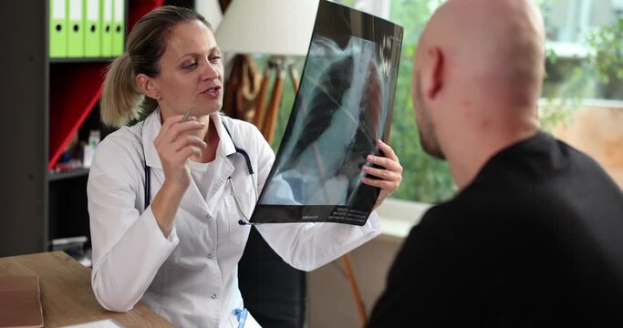 Female doctor in explaining diagnosis on x-ray lung fluorography to male patient during medical appointment in hospital