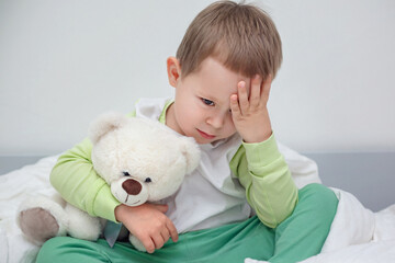 the child is sad, boy 3 years old upset and hugging his teddy bear