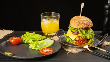 Fresh tasty burger and orange juice on dark background