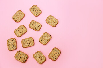 dry square diet crackers with seeds on a pink background