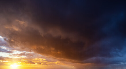 A autumn sunset sky with orange and dark stormy clouds as a background or texture