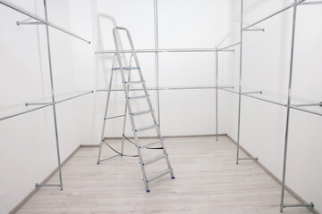 Ladder and metal pipes in empty renovated room