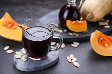 Fresh pumpkin seed oil in glass pitcher on dark grey table