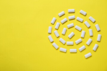 Tasty white chewing gums on yellow background, flat lay. Space for text