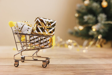 Online christmas shopping and sale. Shopping cart with gift boxes tied golden ribbons and bow on...