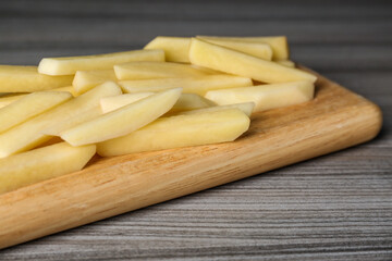 Cut raw potatoes on wooden table, closeup
