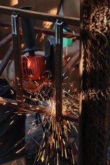 bright sparks flying when the worker grinds the metal structure. Close-up photo
