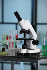 Modern microscope with glass slide on metal table in laboratory