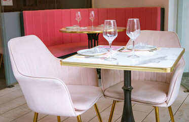 Interior of a stylish luxurious modern cafe, restaurant. A table with two glasses for two beautifully set for a romantic date, a meeting in February 14, Valentine's Day. Pink armchairs in a cozy place