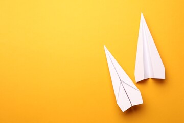 Handmade white paper planes on yellow background, flat lay. Space for text