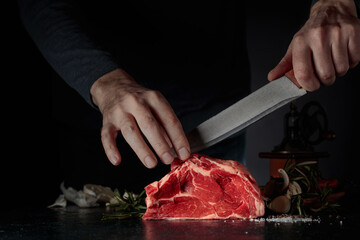 Chef cutting raw beef meat.