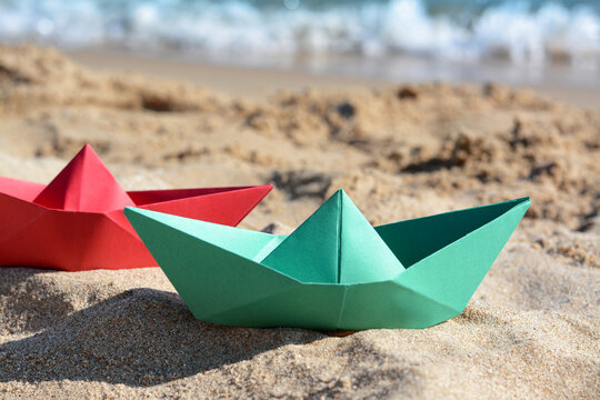 Two paper boats near sea on sunny day, closeup