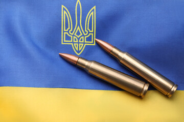 Fototapeta na wymiar Military bullets on Ukrainian flag with trident, top view
