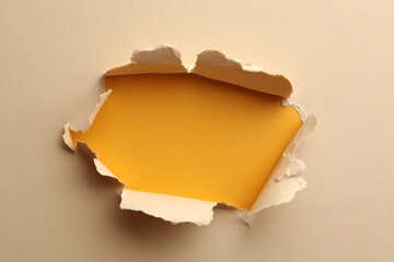 Hole in light beige paper on yellow background