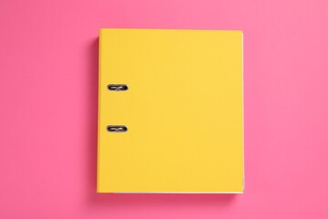 Yellow office folder on pink background, top view