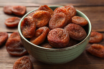 Bowl of tasty apricots on wooden table, closeup. Dried fruits