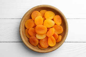 Bowl of tasty apricots on white wooden table, top view. Dried fruits