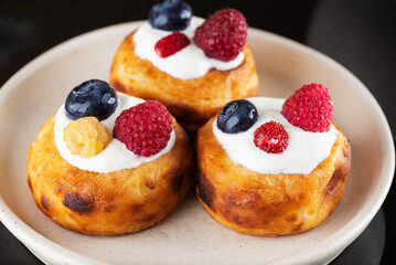 Russian food cheese pancakes with blueberries, raspberries and sour cream on plate.