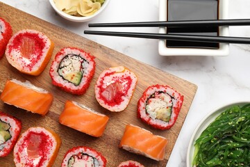 Flat lay composition with delicious sushi rolls on white marble table